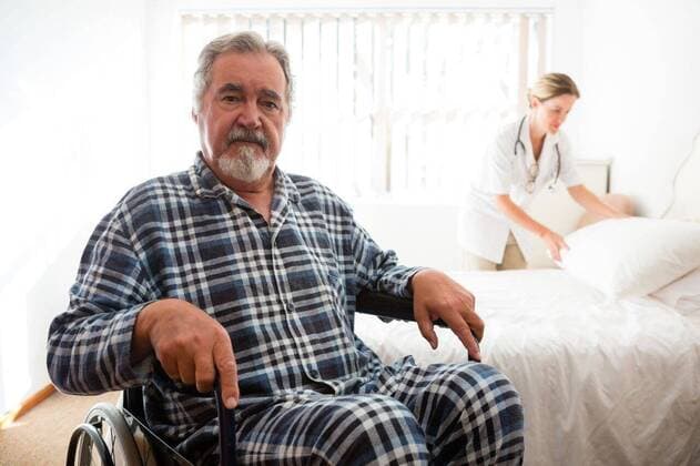 Portrait of senior man sitting on wheelchair while doctor working Portrait of senior man sitting on wheelchair while doctor working in background, model released, , property released, Cape Town, South Africa, 2017-04-27T23:00:00.000Z, 1052197.jpg, sitting, wheelchair, working, senior, sheltered, daycare, lifestyle, retirement, geriatric, retirement home, health, senior citizen, healthcare, medicare, aged, golden years, retirement community, casual, assisted living, together, care, female doctor, doctor, practitioner, specialist, health service, expertise, profession, lab coat, accommodation, nursing home, patient, bed, adjusting, standing, disabled, mobility, support, disability, handicap, accessibility 70s, Senior, Elderly, Man, Male, Cau