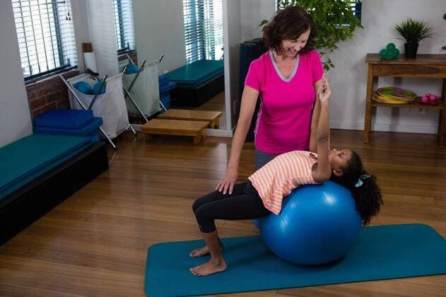 Female physiotherapist helping girl patient in performing stretching exercise on exercise mat Female physiotherapist helping girl patient in performing stretching exercise on exercise mat in clinic, model released, , property released, Cape Town, South Africa, 2017-04-22T23:00:00.000Z, 1052738.jpg, physio, physiotherapy, physiotherapist, practitioner, orthopedic, physical therapy, physical therapist, therapy, clinic, hospital, health service, healthcare, bodycare, healthcare and medicine, sportswear, training, routine, healthy lifestyle, wellness, wellbeing, active, activity, fitness, healthy, physical, determination, exercise, exercising, workout, working out, patient, helping, assistance, smiling, cheerful, interacting, stretching, exe