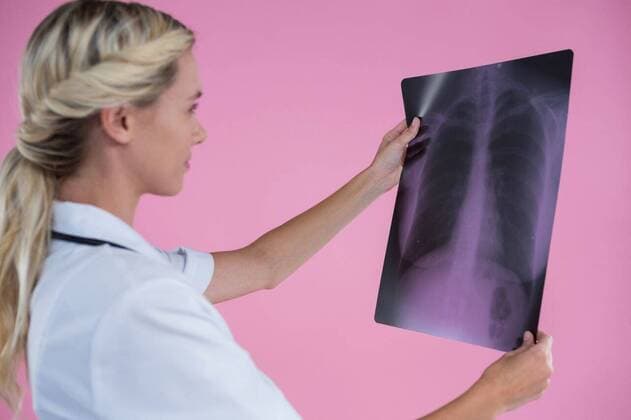 IMAGO Creative: Brustkrebsmonat Side view of young female doctor looking at X-ray Side view of young female doctor looking at X-ray while standing against pink background, model released, Cape Town, South Africa, 26.04.2017, 1055132.jpg, occupation, doctor, stethoscope, medical, lab coat, specialist, healthcare, health service, holding, checking, x-ray, diagnosis, examination, breast cancer, womens health, concentration, pink background, cut out, awareness, icon, cancer, illness, breast cancer awareness, healthcare and medicine, disease, tumor, millennial, standing, blond hair, hairstyle 20s, Young Adult, Woman, Female, Caucasian, 25-29 Years, Young Women, Caucasian Ethnicity Studio shot,Side view,Head and shoulders