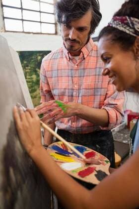 IMAGO Kreativ: Bildung, Kunsterziehung Man assisting woman in painting Man assisting woman in painting during drawing class, model released, , property released, Cape Town, South Africa, 21.04.2017, 1059147.jpg, teacher, instructor, guidance, job, occupation, drawing teacher, profession, professional, artist, expertise, assistance, assisting, casual clothing, drawing class, student, smiling, happy, cheerful, drawing, activity, learning, education, practicing, colorful, watercolor, painting, paint, artwork, paintbrush, pencil, wooden, canvas, easel, palette, creative, creativity, hobby, craft, art and craft, together, modern, beautiful, stylish, millennial 30s, Mid Adult, Man, Male, Caucasian, Woman, Female, Mixed-Race, 35-39 Years, Mid Adult Men, Caucasian Ethnicity, 30-34 Year