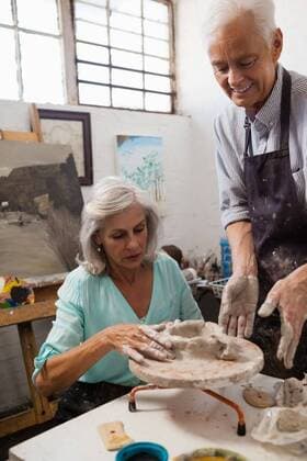 IMAGO Kreativ: Bildung, Kunsterziehung Senior man assisting senior woman in making pottery during drawing class Attentive senior man assisting senior woman in making pottery during drawing class, model released, , property released, Cape Town, South Africa, 21.04.2017, 1059425.jpg, pottery, potter, craftsperson, artist, industry, class, assistance, guidance, profession, professional, job, occupation, apron, learning, practicing, education, assisting, looking, interacting, smiling, art, creating, canvas, easel, painting, pottery wheel, craft product, earthenware, ceramic, clay, pot, molding, molding a shape, shaping, preparing, preparation, perfection, together, expertise, skill, creativity, art and craft, hobby, senior, attentive, focused 50s, Mature Adult, Man, Male, Caucasian