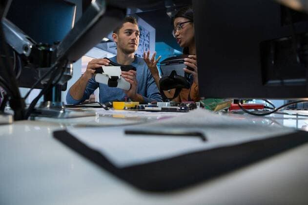 IMAGO Creative: Digitale Welt, Mixed Reality Computer engineers repairing motherboard at desk Computer engineers repairing motherboard at desk in office, model released, , property released, Cape Town, South Africa, 19.08.2017, 1103078.jpg, engineer, computer engineer, repair person, technician, colleague, coworker, teamwork, desk, chair, talking, interacting, showing, holding, communication, computer, virtual reality headset, virtual, desktop pc, electronic, personal computer, working, repair, repairing, maintenance, motherboard, fixing, learning, development, hand tool, work tool, together, millennial 20s, Young Adult, Woman, Female, Mixed-Race, Man, Male, Caucasian, 25-29 Years, Young Women, Mixed-Race Person, Young Men, Caucasian Ethnicity Indoors,Head and shoulders