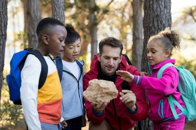 IMAGO Creative: Bildung, Wissenschaftserziehung Teacher and kids examining rock Teacher and kids examining rock in park, model released, , property released, Cape Town, South Africa, 09.05.2017, 1109463.jpg, sunny, summer, park, parkland, student, elementary, assistance, guidance, teacher, job, occupation, professional, casual clothing, school bag, talking, interacting, communication, holding, looking, examining, scrutiny, discovery, experiment, research, touching, rock, stone, science, study, studying, education, leisure, lifestyle, nature, together, handsome, millennial, exploration, adventure, recreation, smart, childhood, cute, attentive 20s, Young Adult, Man, Male, Caucasian, Child, Boy, Chinese, Black, Girl, Female, Mixed-Race, 25-29 Years, Young Men, Caucasian Ethnicity, 6-7 Year