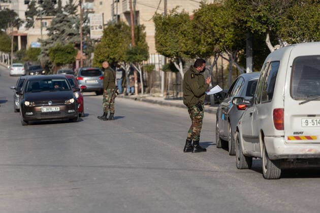(210224) -- BETHLEHEM, Feb. 24, 2021 -- Palestinian police officers work at a checkpoint at one of the main roads of Beit Sahour near the West Bank city Bethlehem, Feb. 24, 2021. The Governor of Bethlehem announced the closure of Beit Sahour for 48-hours starting from 12:00 am Wednesday, after increase of the numbers of COVID-19 infections. (Photo by Xinhua) MIDEAST-BETHLEHEM-COVID-19-CHECKPOINT LuayxSababa 