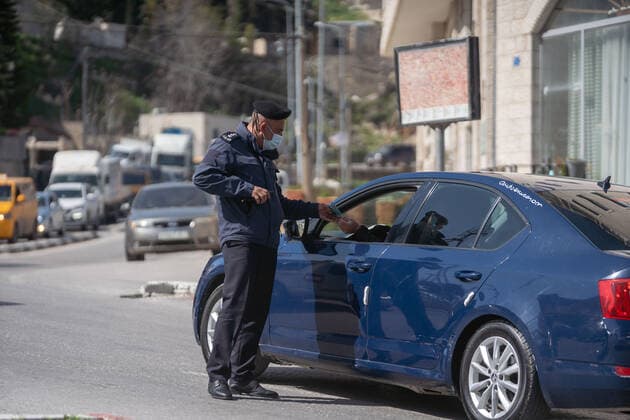 (210224) -- BETHLEHEM, Feb. 24, 2021 -- A Palestinian police officer works at a checkpoint on one of the main roads in Beit Sahour near the West Bank city of Bethlehem, Feb. 24, 2021. The Governor of Bethlehem announced the closure of Beit Sahour for 48-hours starting from 12:00 am Wednesday, after increase of the numbers of COVID-19 infections. (Photo by Xinhua) MIDEAST-BETHLEHEM-COVID-19-CHECKPOINT LuayxSababa 