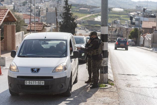 (210224) -- BETHLEHEM, Feb. 24, 2021 -- Palestinian police officers work at a checkpoint at one of the main roads of Beit Sahour near the West Bank city Bethlehem, Feb. 24, 2021. The Governor of Bethlehem announced the closure of Beit Sahour for 48-hours starting from 12:00 am Wednesday, after increase of the numbers of COVID-19 infections. (Photo by Xinhua) MIDEAST-BETHLEHEM-COVID-19-CHECKPOINT LuayxSababa 