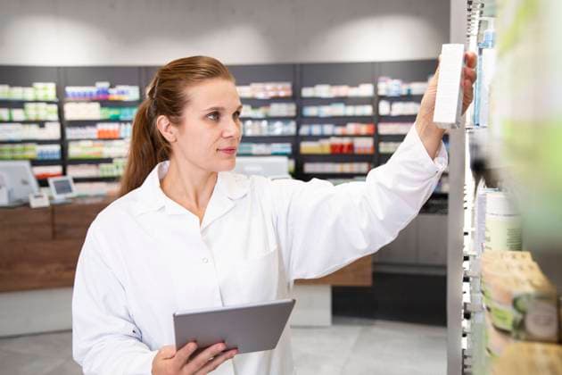 Female pharmacist with digital tablet checking medicine in store model released Symbolfoto property released FKF04005