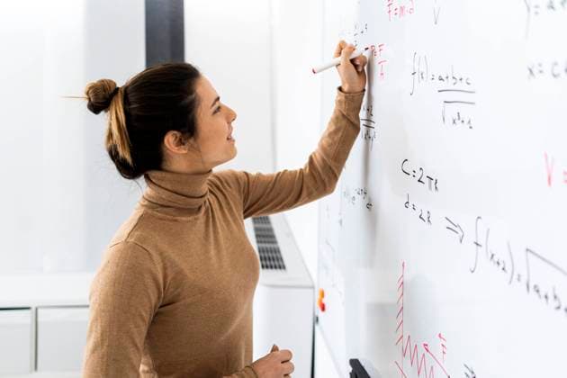 Smiling young woman solving mathematical formula on whiteboard at home model released Symbolfoto property released GIOF10662