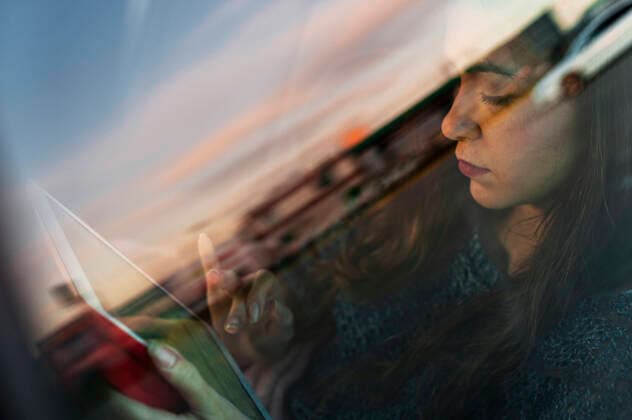 Young woman using digital tablet while travelling in car seen through glass window model released Symbolfoto JMPF00875