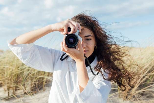 Woman with long hair photographing through vintage camera against sky model released Symbolfoto JRVF00257