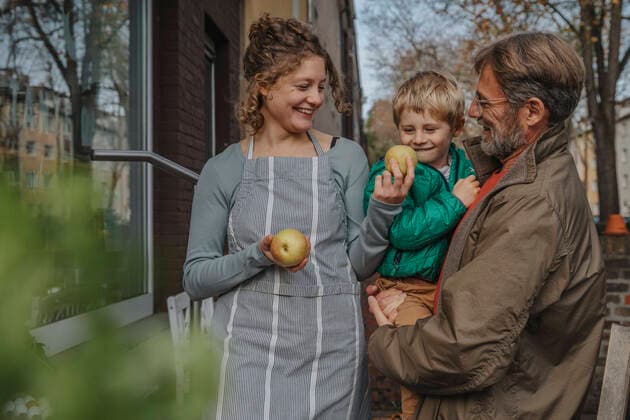 Smiling saleswoman selling apple to father and son at retail store model released Symbolfoto property released MFF06884