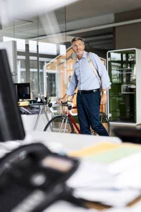 Businessman with bicycle and bag looking away while walking at office model released Symbolfoto property released PESF02526
