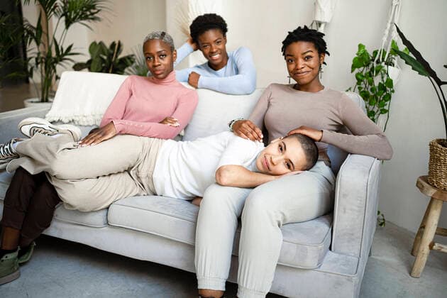 Smiling female friends on sofa in living room at home model released Symbolfoto property released RCPF00733