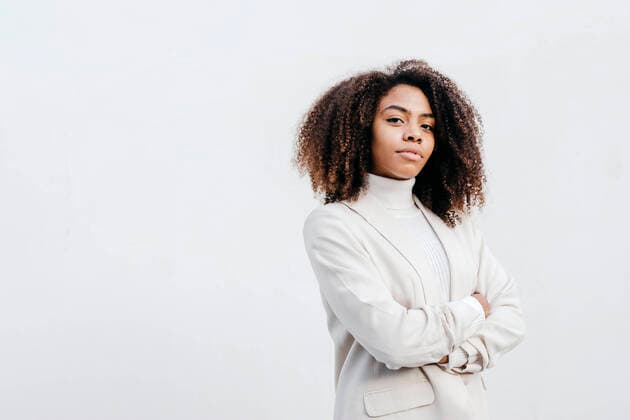Confident young woman with arms crossed standing against white wall model released Symbolfoto TCEF01439