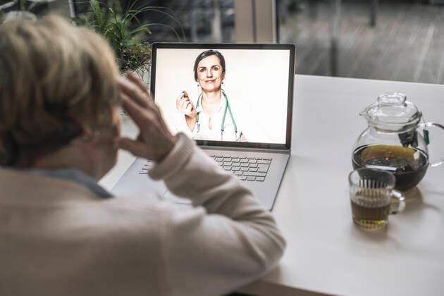 Senior woman taking advice from female doctor through video call in living room model released Symbolfoto property released UUF22659