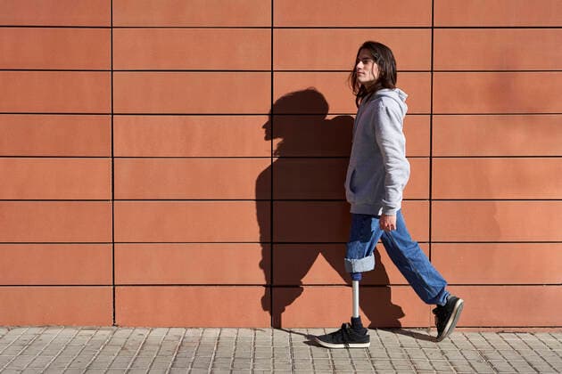 IMAGO Creative: NGO, Rehabilitation und Gesundheitswesen Disabled man with prosthetic leg walking by wall while looking away model released Symbolfoto VEGF03774