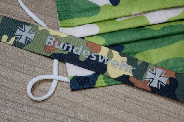 Mundschutzmaske und Bundeswehr Mundschutzmaske und Bundeswehr, 24.02.2021, Borkwalde, Brandenburg, Auf einer Mundschutzmaske liegt ein Band mit der Aufschrift Bundeswehr.