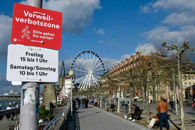 F95 - H96 Düsseldorf, NRW 26.2.2021, Corona, Bitte gehen Sie weiter: Aufgrund der Menschenansammlungen am vergangenen Wochenende hat die Stadt Düsseldorf ein Verweilverbot für die Rheinuferpromenade in der Altstadt festgelegt. Dieses gilt an Freitagen von 15:00 Uhr bis 1:00 Uhr und an Sa So. von 10:00 bis 1:00 Uhr. Noch ist es 14:50 am Freitag und Menschen nutzen die Zeit auf den Parkbänken.