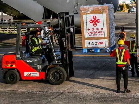 (210228) -- MANILA, Feb. 28, 2021 -- Staff members unload vaccines donated by China at a Philippine Air Force base in Manila, the Philippines, on Feb. 28, 2021. A batch of Sinovac vaccine CoronaVac donated by China arrived in the Philippines on Sunday, the first COVID-19 vaccine to reach the Southeast Asian country. The delivery of the vaccines allows the Philippines to start mass vaccinations soon, marking a new phase in the country s fight against the COVID-19 that infected 576,352 and killed 12,318. ) PHILIPPINES-MANILA-COVID-19-VACCINE-ARRIVAL ROUELLExUMALI 