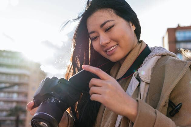 IMAGO Creative: Kreative Renaissance -- der junge Entrepreneur Ethnic young happy Asian female photographer shooting photo on professional photo camera on city street Copyright: xDavidxMunozx Model Released