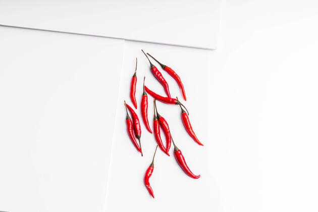IMAGO Creative: Clickbait, Rezepte und Kochen High angle composition of hot red chili peppers arranged plate against white board surface background Copyright: xJavierxDexLaxTorrex Model Released