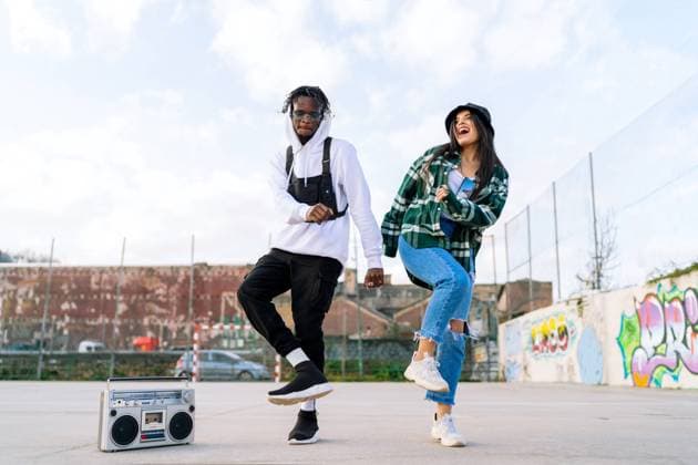 Young glad stylish multiracial partners dancing hip hop on pavement near retro tape recorder under cloudy sky in town Copyright: xLuisxManuelxMunozx Model Released