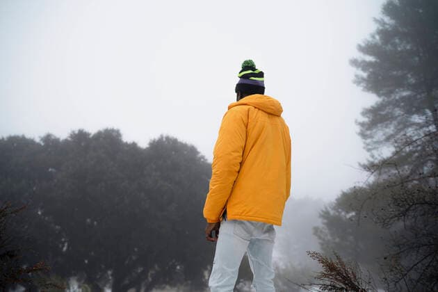 IMAGO Creative: Wintersport, Mode Back view of unrecognizable African American man with hands and pockets wearing outerwear standing in snowy park Copyright: xOscarxDexDiosx Model Released