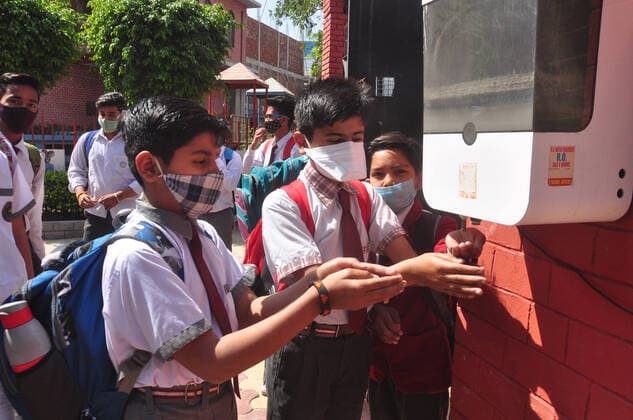 GHAZIABAD, INDIA - MARCH 1: Students sanitizing their hands while arrive to attend classes at a primary school as it reopens for the first time since lockdown due to Covid-19 at Kavi Nagar on March 1, 2021 in Ghaziabad, India. Nearly a year after the Centre imposed a nationwide lockdown due to the COVID-19 outbreak, several states and UTs have decided to reopen schools and colleges from March 1. As the deadly virus cases are now steadily dropping, the offline classes are going to resume in states such as Bihar, Meghalaya, Jammu and Kashmir, Haryana, among others. (Photo by Sakib Ali Hindustan Times) Primary Schools Reopen For The First Time Since Lockdown Due To Covid-19