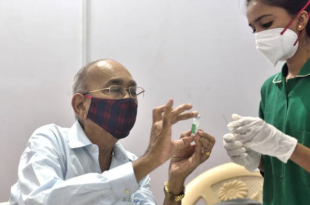 MUMBAI, INDIA - MARCH 1: A senior citizen inspects a Covishield vial while getting their first dose of a Covid-19 vaccination, at BKC on March 1, 2021 in Mumbai, India. India?s Covid-19 vaccination drive was extended today to include the elderly and those with co-morbidities. (Photo by Satish Bate Hindustan Times) Covid Vaccination Phase 2 Starts In India