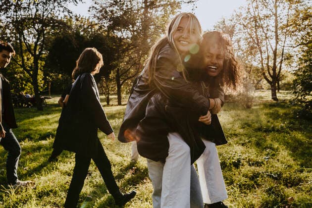 Young woman carrying piggyback to female friend in park Germany, Berlin, model released Copyright: xMaskotx , MA84385