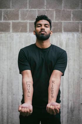 IMAGO Creative: Tag der Menschenrechte am 10. Dezember Portrait of male activist showing equal rights written on hand against wall Sweden, Stockholm, model released Copyright: xMaskotx , MA84422
