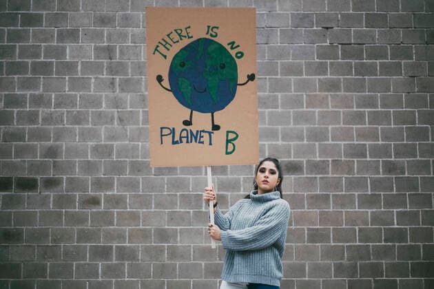 Young female activist holding planet earth poster against wall during social movement Sweden, Stockholm, model released Copyright: xMaskotx , MA84439