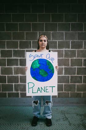 Female protestor with planet earth poster standing on footpath against wall Sweden, Stockholm, model released Copyright: xMaskotx , MA84492