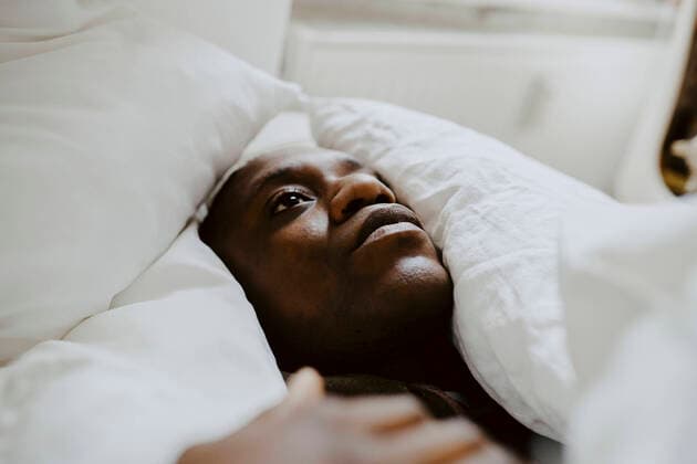 IMAGO Creative: Kulturelle Folgen der Pandemie: Gesundheitsbewußtsein und Alleinsein Depressed man lying amidst pillow in bedroom Germany, Berlin, model released, property released Copyright: xMaskotx , MA84898
