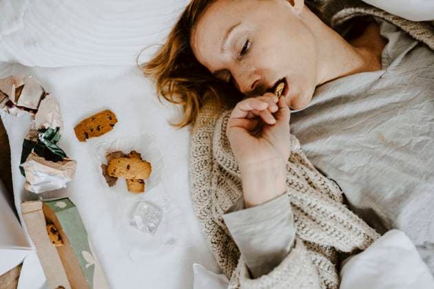 IMAGO Creative: Gesundheit, Magersucht, Bulimie High angle view of woman eating cookie while lying on bed at home Germany, Berlin, model released, property released Copyright: xMaskotx , MA84910