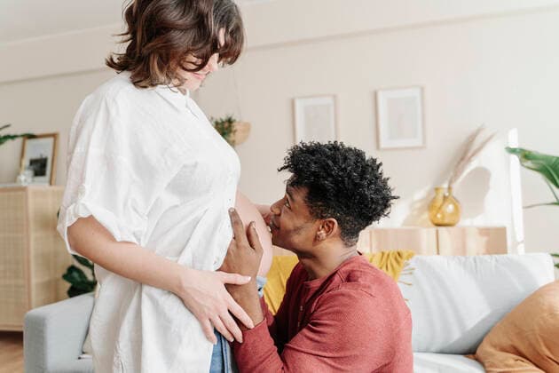 IMAGO Creative: Vaterschaft Tender black man kissing tummy of pregnant woman Sant Cugat del Vallès, CT, Spain CR_KTUU210303B-639666-01 ,model released, Symbolfoto ,property released