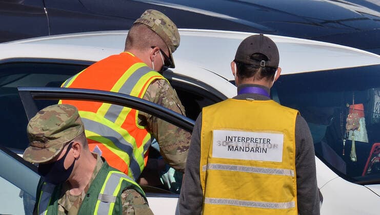 A Mandarin interpreter assists military personnel in administering COVID-19 shots to local residents at a drive-through vaccination site on the Cal State LA campus in Los Angeles on Thursday, March 4, 2021. California will begin sending 40% of all vaccine doses to the most vulnerable neighborhoods in the state to try to inoculate people most at risk from the coronavirus and get the state s economy open more quickly, Gov. Gavin Newsom said Thursday in the latest shake-up to the state s rules.  LAP2021030437 JIMxRUYMEN