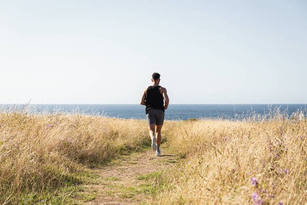 IMAGO Creative: Kulturelle Folgen der Pandemie: Gesundheitsbewu?tsein und Alleinsein Muscular male jogger running along path in meadow during training on background of sea in summer Copyright: xAndresxVictorerox Model Released