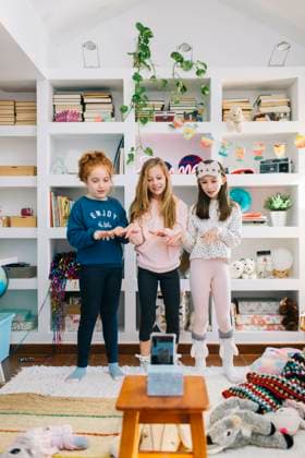 IMAGO Creative: Jahreszeit Winter, Fantasievoll drinnen spielen Full length of happy little girls in casual clothes standing in playroom against mobile phone while filming video of dance Copyright: xLightsyx Model Released