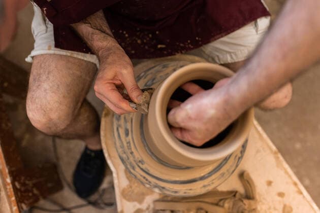 Crop unrecognizable sculptor with equipment giving shape while sculpting with brown clay on throwing wheel, Model released Copyright: xMiguelxVallsx MR