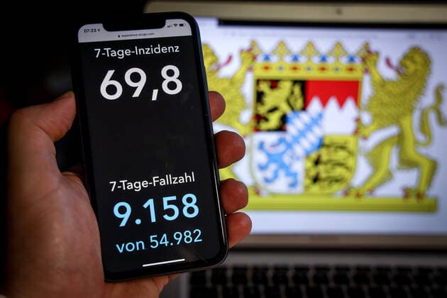 Coronavirus in Deutschland - Covid-19-Dashboard des Robert Koch-Institut DEU, Deutschland, Bayern, 07.03.2021: Die 7-Tage-Inzidenz für das Bundesland (Fälle letzte 7 Tage 100.000 EW) wird auf einem iPhone angezeigt, im Hintergrund das Landeswappen