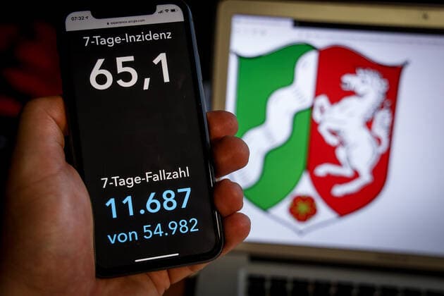 Coronavirus in Deutschland - Covid-19-Dashboard des Robert Koch-Institut DEU, Deutschland, Nordrhein-Westfalen, 07.03.2021: Die 7-Tage-Inzidenz für das Bundesland (Fälle letzte 7 Tage 100.000 EW) wird auf einem iPhone angezeigt, im Hintergrund das Landeswappen