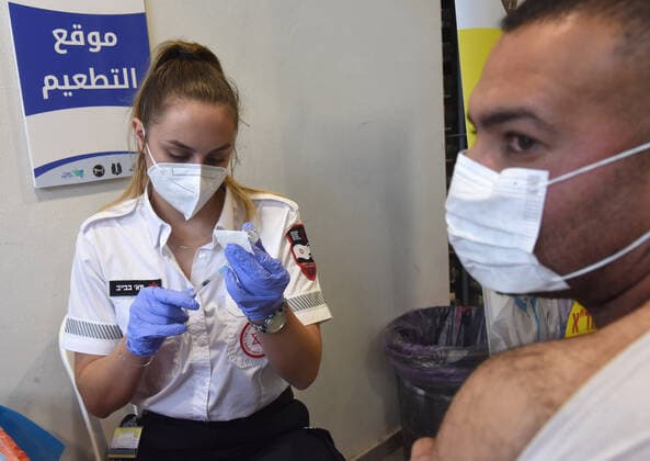 A medic from Israel s Magen David Adam emergency agency prepares to inoculate a Palestinian worker with the first dose of the Moderna?s COVID-19 vaccine at the Lamed Hei Checkpoint between Gush Etzion and Beit Shemesh, on Monday, March 8, 2021. Israel started a two week campaign to vaccine some 100,000 Palestinian workers from the West Bank who hold permits to work in Israel and Jewish settlements. The vaccination campaign is a joint project by the Israeli Heath Ministry, Ministry of Defense, Land Crossing Authority and the Coordination of Government Activities in the Territories.  JER2021030801 DEBBIExHILL