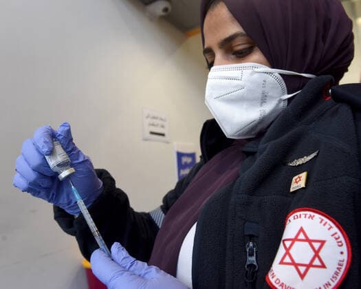 A medic from Israel s Magen David Adam emergency agency prepares to inoculate a Palestinian worker with the first dose of the Moderna COVID-19 vaccine at the Lamed Hei Checkpoint between Gush Etzion and Beit Shemesh, on Monday, March 8, 2021. Israel started a two week campaign to vaccine some 100,000 Palestinian workers from the West Bank who hold permits to work in Israel and Jewish settlements. The vaccination campaign is a joint project by the Israeli Heath Ministry, Ministry of Defense, Land Crossing Authority and the Coordination of Government Activities in the Territories.  JER2021030804 DEBBIExHILL