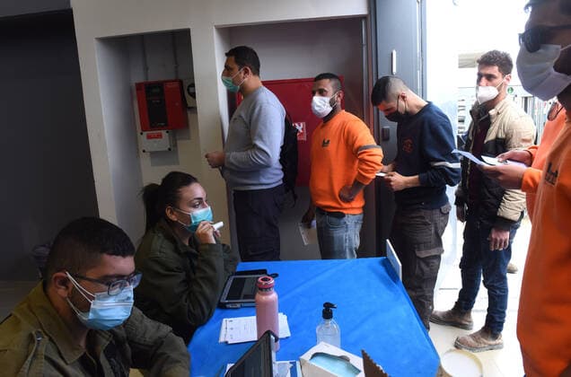 Palestinian workers wait in line to receive the first dose of the Moderna COVID-19 vaccine at the Lamed Hei Checkpoint between Gush Etzion and Beit Shemesh, on Monday, March 8, 2021. Israel started a two week campaign to vaccine some 100,000 Palestinian workers from the West Bank who hold permits to work in Israel and Jewish settlements. The vaccination campaign is a joint project by the Israeli Heath Ministry, Ministry of Defense, Land Crossing Authority and the Coordination of Government Activities in the Territories.  JER2021030802 DEBBIExHILL