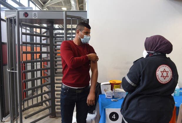A medic from Israel s Magen David Adam emergency agency inoculates a Palestinian worker with the first dose of the Moderna COVID-19 vaccine at the Lamed Hei Checkpoint between Gush Etzion and Beit Shemesh, on Monday, March 8, 2021. Israel started a two week campaign to vaccine some 100,000 Palestinian workers from the West Bank who hold permits to work in Israel and Jewish settlements. The vaccination campaign is a joint project by the Israeli Heath Ministry, Ministry of Defense, Land Crossing Authority and the Coordination of Government Activities in the Territories.  JER2021030814 DEBBIExHILL