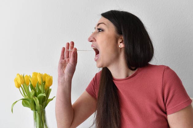 Themenbild Corona Antigen Test,Schnelltest, Coronaschnelltest.Selbsttest. Jeder Bundesbuerger soll einen Anspruch auf einen kostenlosen Schnelltest pro Woche haben. Eine junge Frau fuehrt einen Selbstest aus und macht einen Rachenabstrich zu Hause, MODEL RELEASED!