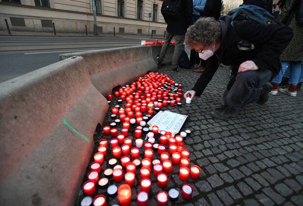 A man, wearing respirator to prevent the spread of the coronavirus, lays down candle during the rally of group Let Us Stop COVID called Let Us Save Lives, Let Us Stop Industry in front of the Government Office in Prague, Czech Republic, March 9, 2021. (CTKxPhoto MichaelaxRihova) CTKPhotoP202103090814601  mir 14