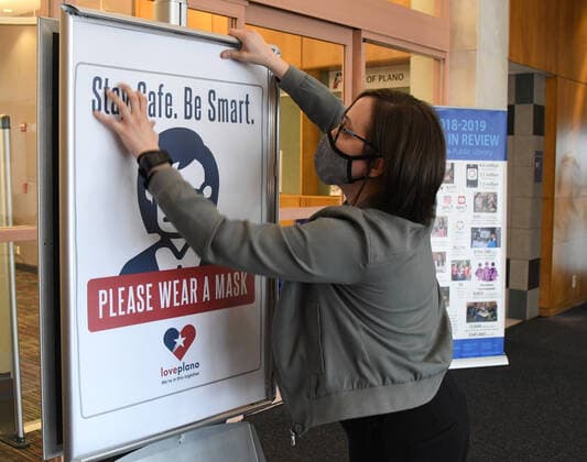 Workers at a public library in Plano, Texas change out signs requiring mask to enter on Tuesday, March 9, 2021 in preparation for changes in the state s mask mandate. Texas Gov. Greg Abbott fully rescinded the statewide mask order and is allowing business to reopen at full capacity effective March 10, 2021 leaving organizations and businesses to determine if they want to require customers to wear masks or not.  DAL2021030903 IANxHALPERIN