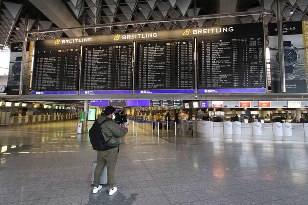Ein Reisender steht vor der Anzeigetafel in der Abflughalle B im nahezu menschenleeren Terminal 1 im Flughafen Frankfurt, Hessen, Deutschland